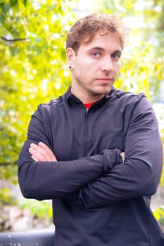 Young Caucasian sportsman with defiant look and crossed arms looks at the camera