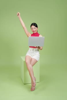 A joyful woman celebrating success while working on her laptop
