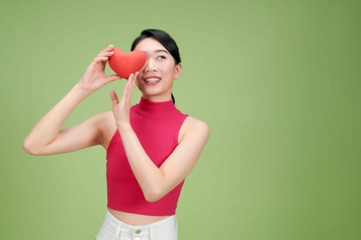 Woman Holding Red Heart Against Green Background Smiling