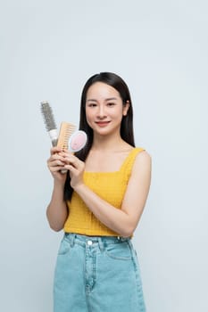 Smiling Woman Holding Hair Brushes And Combs On White Background