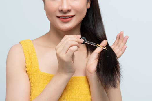 Smiling Woman Applying Hair Serum to Healthy Hair