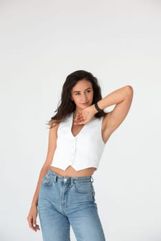 Happy beautiful girl posing in a new hot summer look. Wearing blue jeans and white waistcoat.