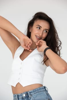 Happy beautiful girl posing in a new hot summer look. Wearing blue jeans and white waistcoat.