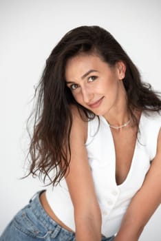 Happy beautiful girl posing in a new hot summer look. Wearing blue jeans and white waistcoat.