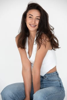 Happy beautiful girl posing in a new hot summer look. Wearing blue jeans and white waistcoat.