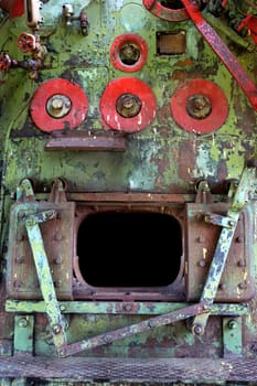 A fragment of a steam boiler with an open firebox in the cabin of an abandoned, non-working locomotive.