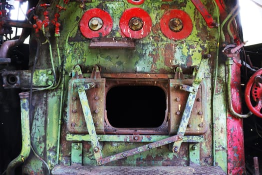 A fragment of a steam boiler with an open firebox in the cabin of an abandoned, non-working locomotive.