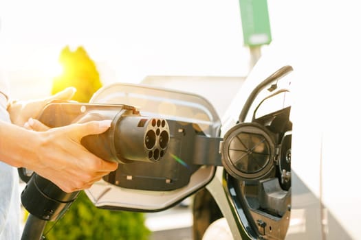 a girl charges her electric car at a charging station, Environmentally friendly energy sources, green energy concept, solar energy