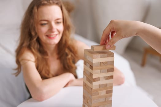 two women playing Jenga board game at home, excitement and relaxation, mind development concept, girl hands playing wooden game Django