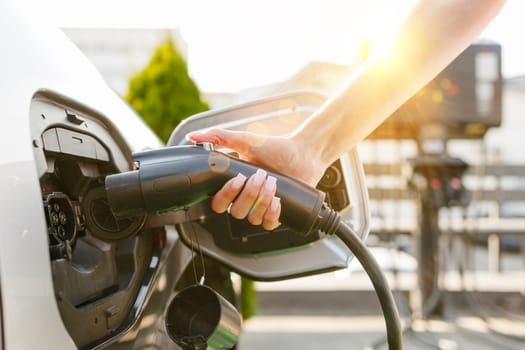 a girl charges her electric car at a charging station, Environmentally friendly energy sources, green energy concept, solar energy