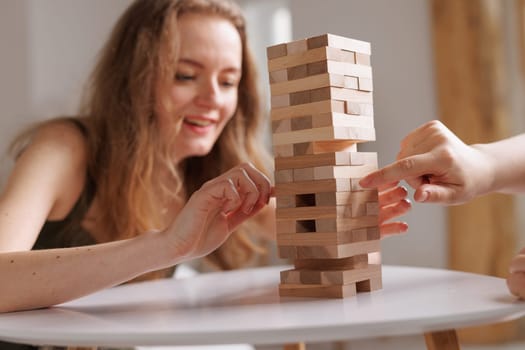two women playing Jenga board game at home, excitement and relaxation, mind development concept, girl hands playing wooden game Django