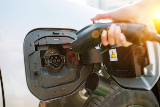 a girl charges her electric car at a charging station, Environmentally friendly energy sources, green energy concept, solar energy