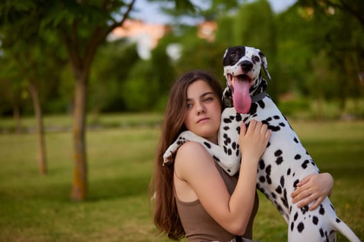 a young girl plays with a dalmatian in the park. dog care concept, love for animals concept