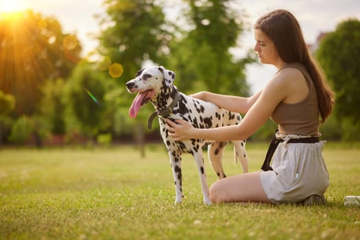 a young girl plays with a dalmatian in the park. dog care concept, love for animals concept
