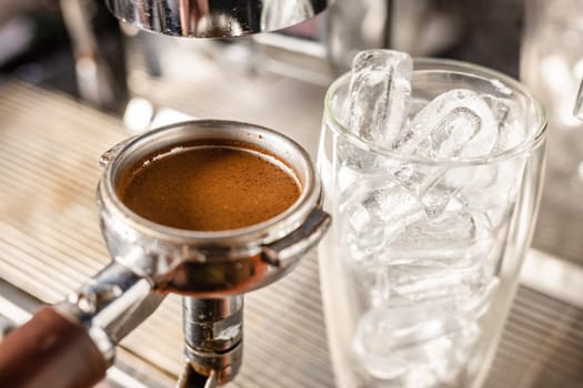 the barista's hand holds a cone with ground coffee near the coffee machine and prepares cold coffee, the barista prepares ice latte