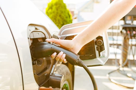 a girl charges her electric car at a charging station, Environmentally friendly energy sources, green energy concept, solar energy