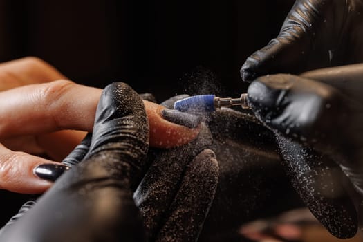 A manicurist gives a hardware manicure to a client using special tools. nail salon, self care concept