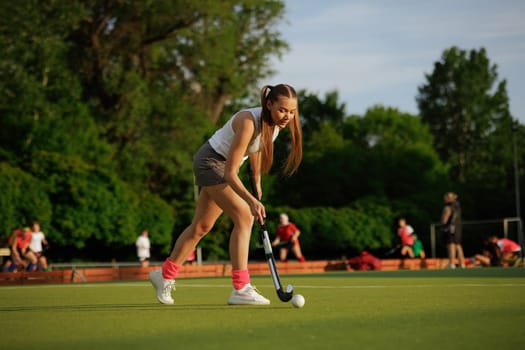 girl hockey player plays field hockey on a sunny day, female hockey player hits the ball with a stick, field hockey concept