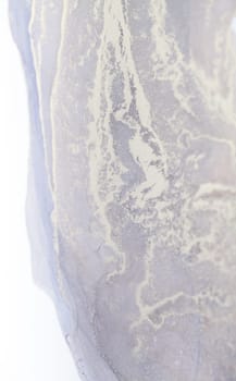 A close-up photo of an abstract fluid painting featuring swirls and patterns in white and grey hues.