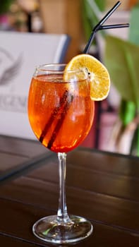 Alcocolous orange cocktail aperol syringe in glass with orange slice in restaurant on table, close-up, vertical