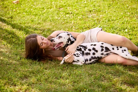 a young girl plays with a dalmatian in the park. dog care concept, love for animals concept