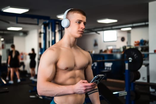 Man using phone while wearing headphones at the gym.
