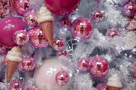 Christmas tree adorned with pink and white decorations, ice cream cones, and natural material ornaments. A creative arts display with magenta artwork and festive jewellery for the holiday event