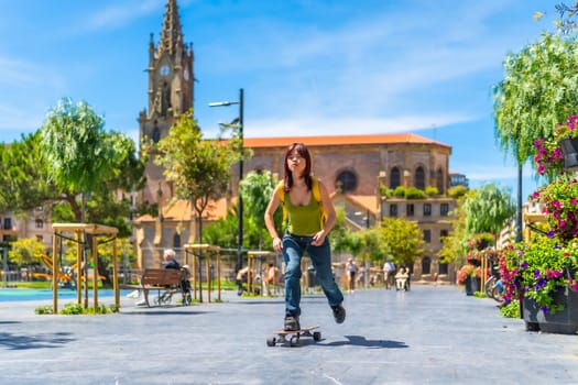 Chinese young woman skateboarding downtown in square in a sunny day of summer