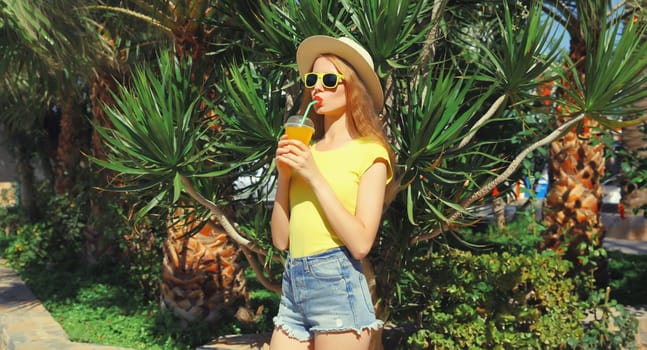 Summer vacation, tourism, happy young woman drinking fresh juice in straw tourist hat standing on the beach with palm tree
