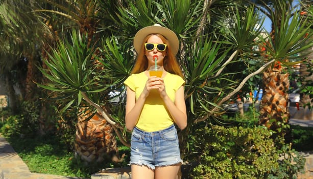 Summer vacation, tourism, happy young woman drinking fresh juice in straw tourist hat standing on the beach with palm tree