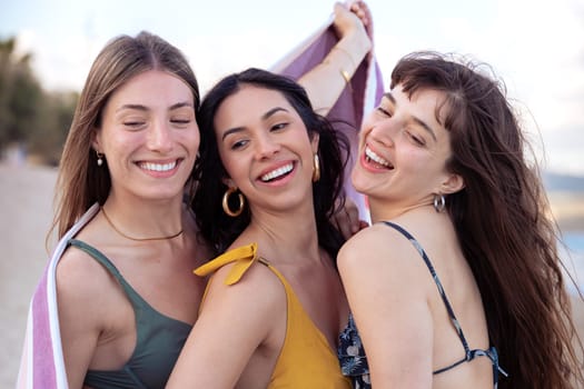 Cheerful multiethnic friends with sunglasses happy on vacation on the beach, looking at the camera.