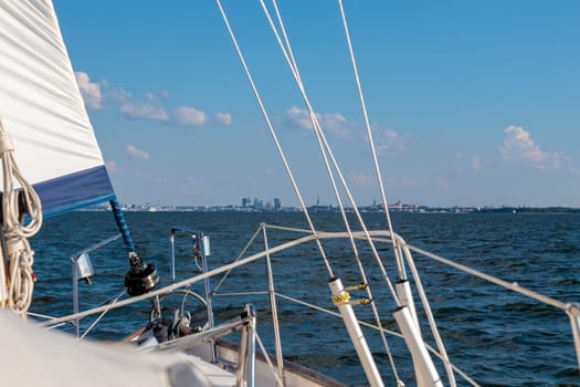 Luxury cruise on a sailing rigged yacht under a genoa sailing towards a shore. City, town on coastline, Tallinn, Estonia, Gulf of Finland, summer sailing