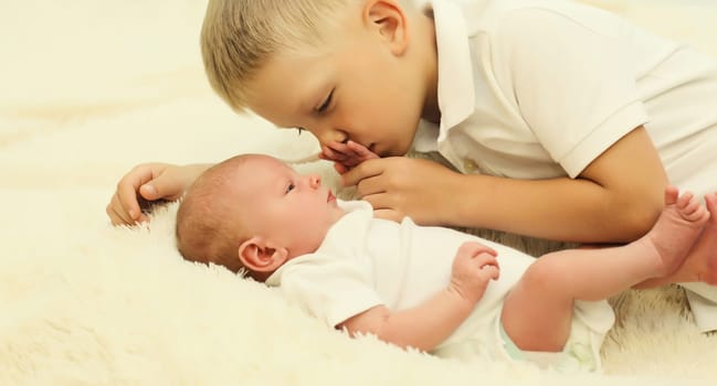 Two children lying on bed, eldest brother and sleeping youngest brother baby at home
