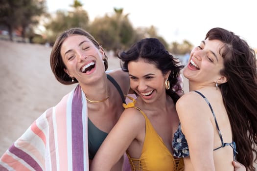 Cheerful multiethnic friends happy on vacation on the beach, looking at the camera.