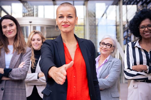 Multiracial happy business women pointing fingers looking at the camera with arms crossed.