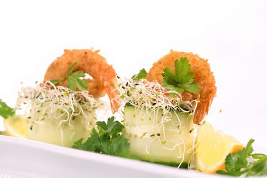 Cucumber appetizer with fried breaded shrimp on a bed of microgreens