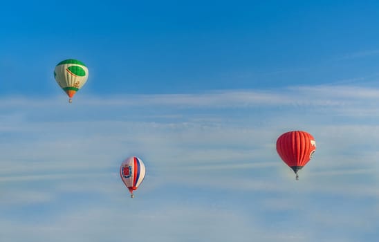 Balloons of different colors soar in the blue sky with light clouds, Belarus, Minsk, Europe