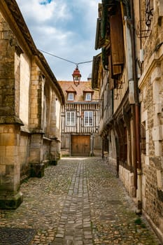 street with old half-timbered houses with wooden shutters and an old street lamp above the street in the town of Honfleur in France