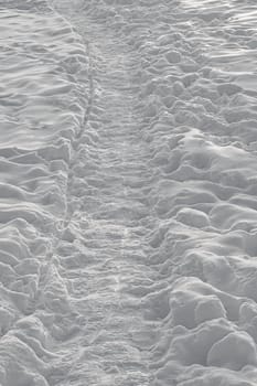 Path and footprints on the snow surface in the evening.