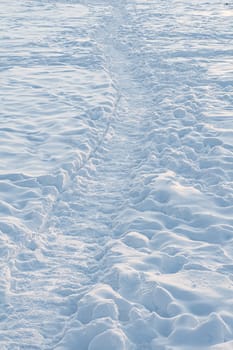 A large path in the snow illuminated by the setting sun.