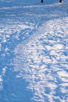 Footprints, path, shadows on the snow surface.