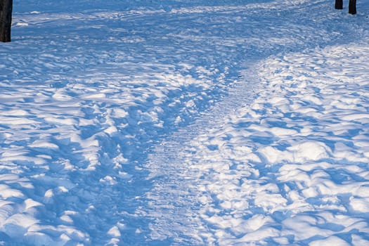 Footprints, path, shadows on the snow surface.