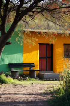 Serene green and yellow adobe house with a striking red door, complemented by a peaceful shaded sitting area