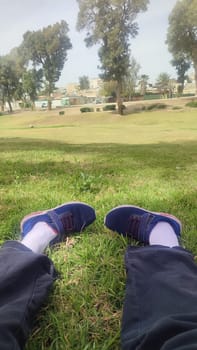 legs of a man in sneakers on green grass. High quality photo