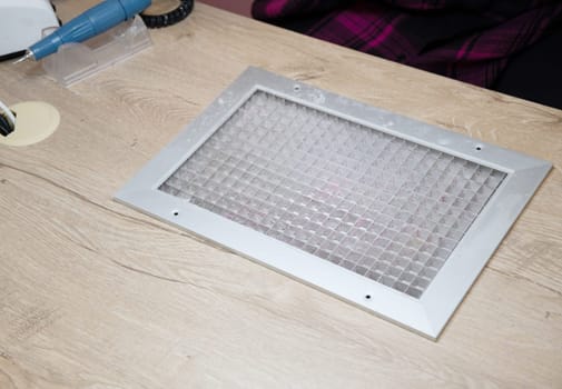 Tabletop dust collector net made of brushed stainless steel, built into the manicurist's table to suck up dust when sharpening nails with a file or milling cutter