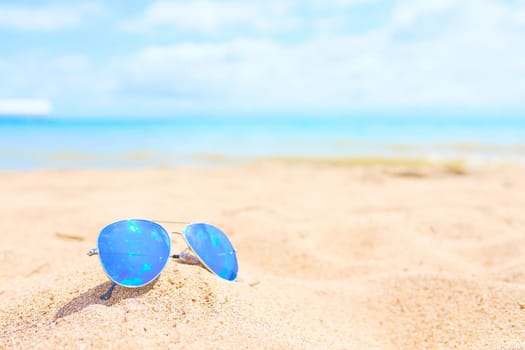 Sunglasses on the beach with ocean and sky on background