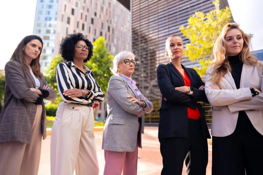 Five businesswomen standing side by side with their arms crossed looking at the camera smiling. Suitable for team, friendship and diversity concepts.