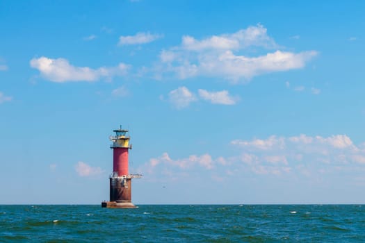 A lighthouse in the Baltic Sea in the Gulf of Finland near Tallinn, Estonia. Blue morning sky, clouds, waves, sea. Banner with copy space