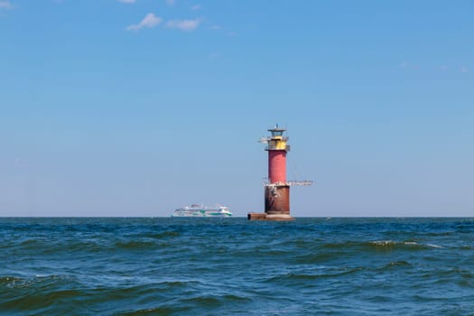 Gulf of Finland, Estonia, June 28, 2024 -A lighthouse in the Baltic Sea near Tallinn and ferry Tallink from Helsinki. Blue sky, clouds, waves, sea. Banner with copy space