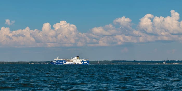 Gulf of Finland, Estonia, June 30, 2024 - Eckero line ferry boat Finlandia in Baltic sea on the horizon. Blue sky, clouds, waves, sea. Banner with copy space
